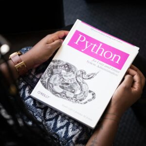 A person reads 'Python for Unix and Linux System Administration' indoors.